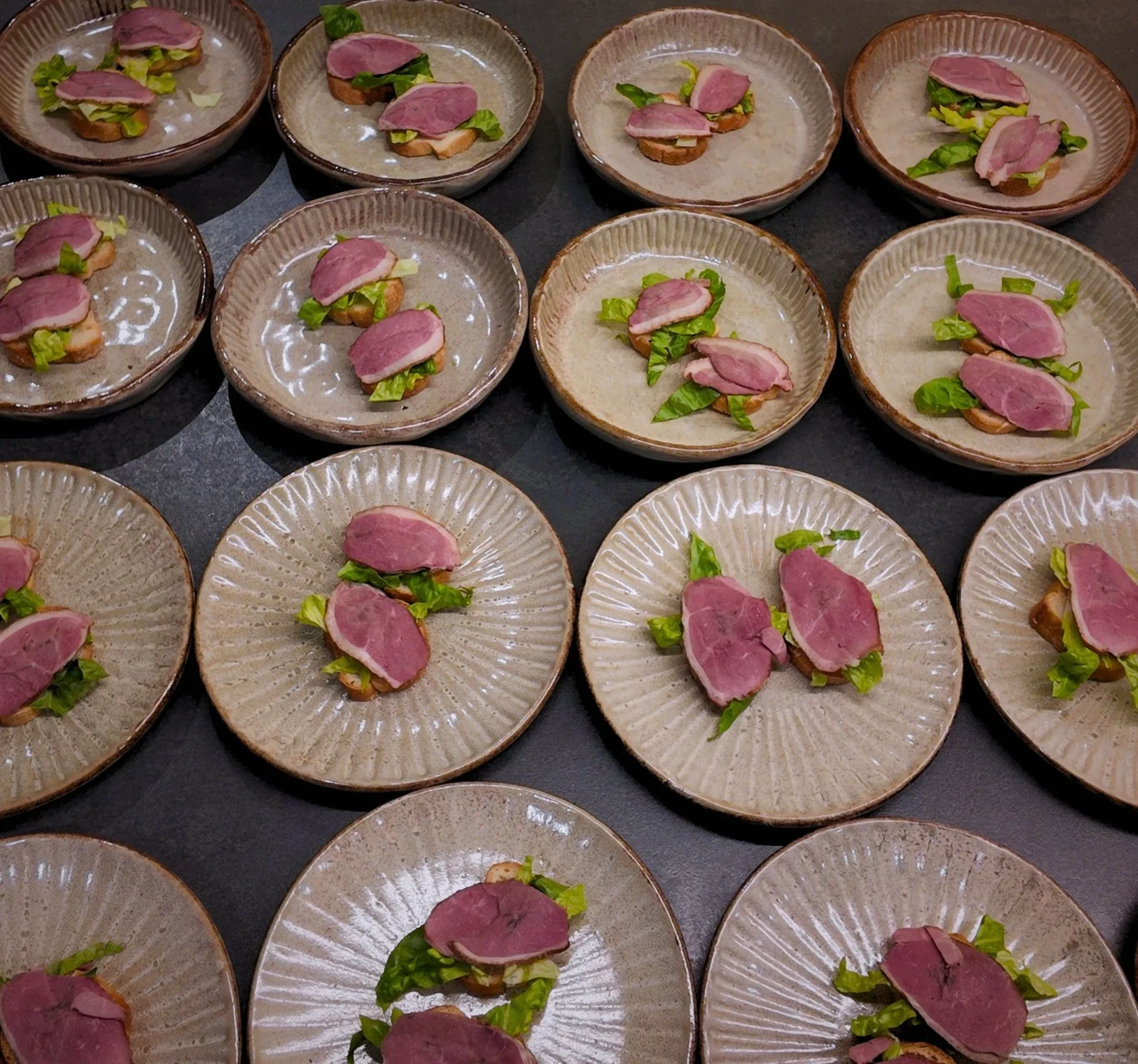 Small plated bites with pink and green garnishes ready for service