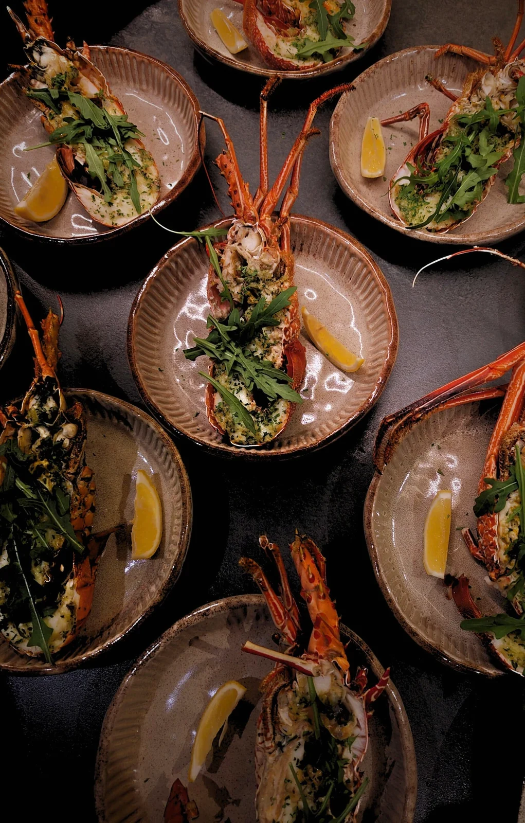 Plates of grilled lobster with greens, arranged for service