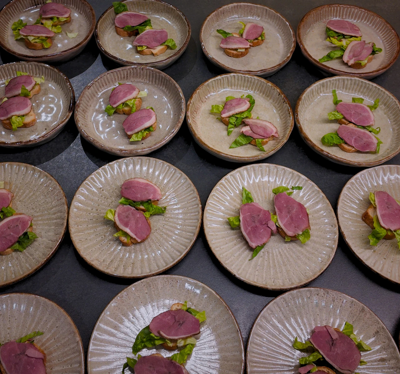 Small plated bites with pink and green garnishes ready for service