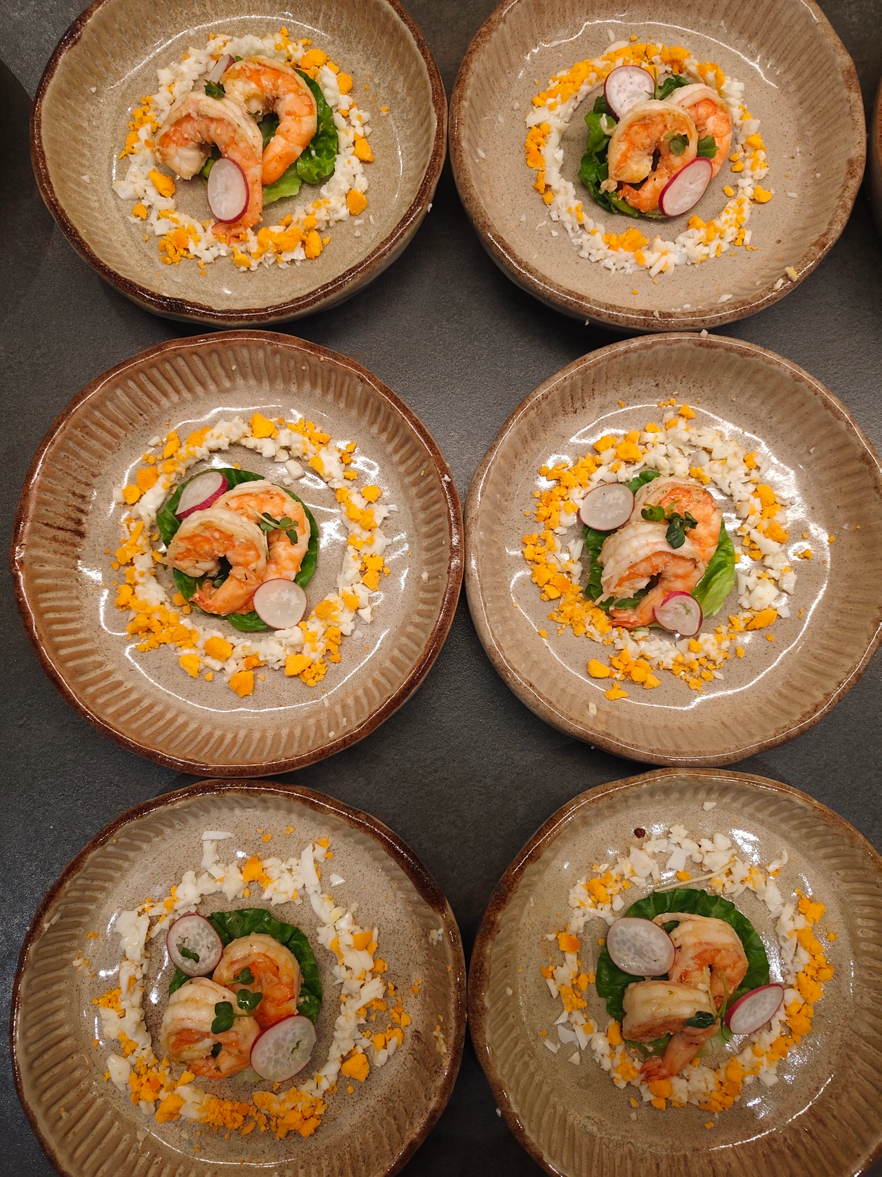 Prawn starters with sliced radish and chopped egg on ceramic plates