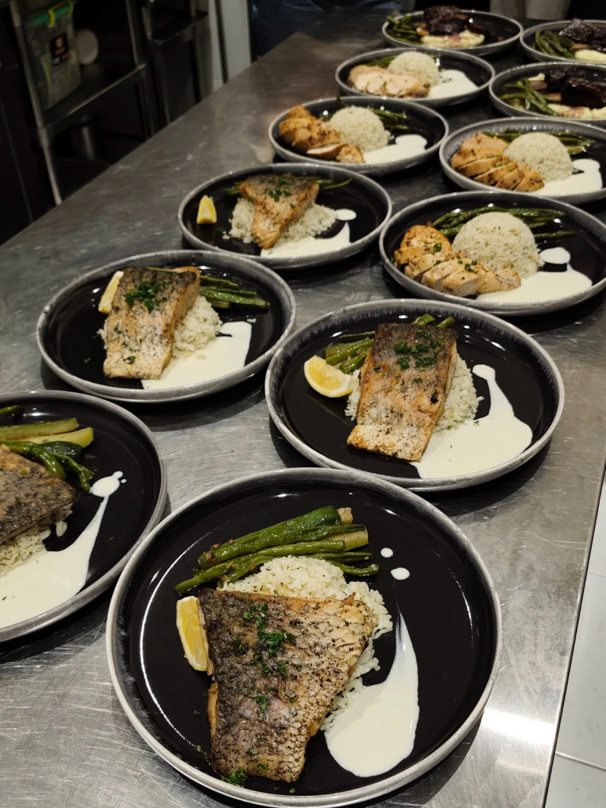 Plates of fish and chicken with rice and vegetables ready for service